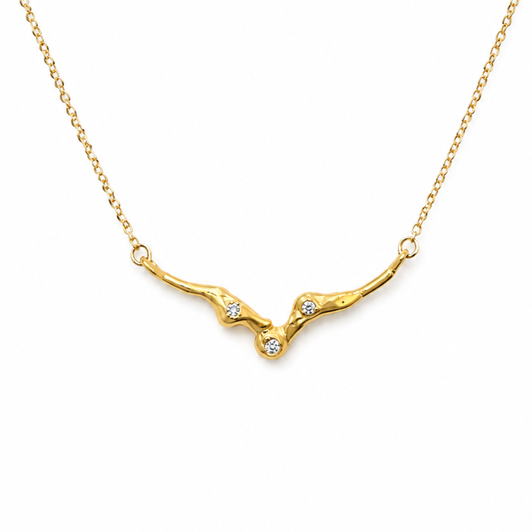 A delicate gold chain necklace featuring a branch-like pendant with small clear gemstones, displayed against a solid white background.