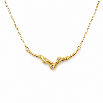 A delicate gold chain necklace featuring a branch-like pendant with small clear gemstones, displayed against a solid white background.