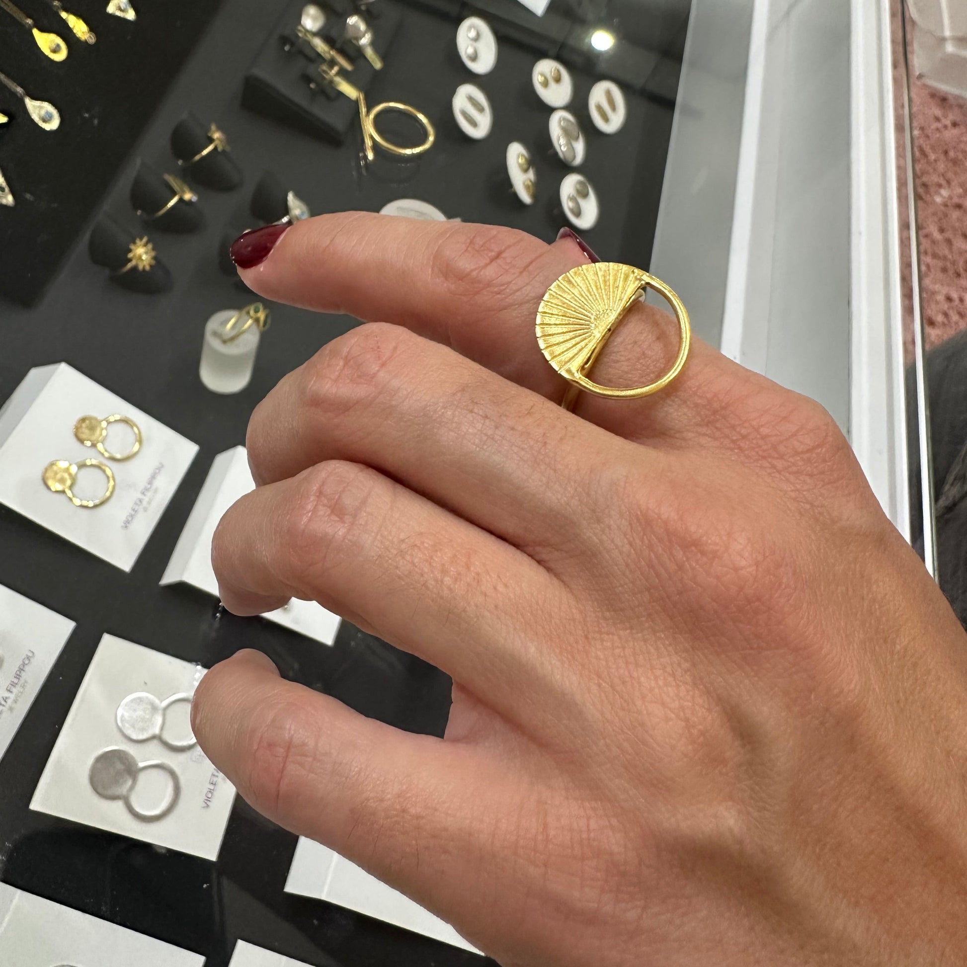 Hand wearing a gold ring over a display of jewelry