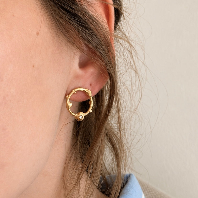 Pair of gold hoop earrings with small stones on a white background