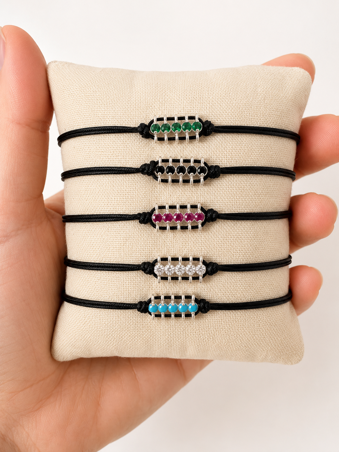 Black cord bracelet with green beads on a white background