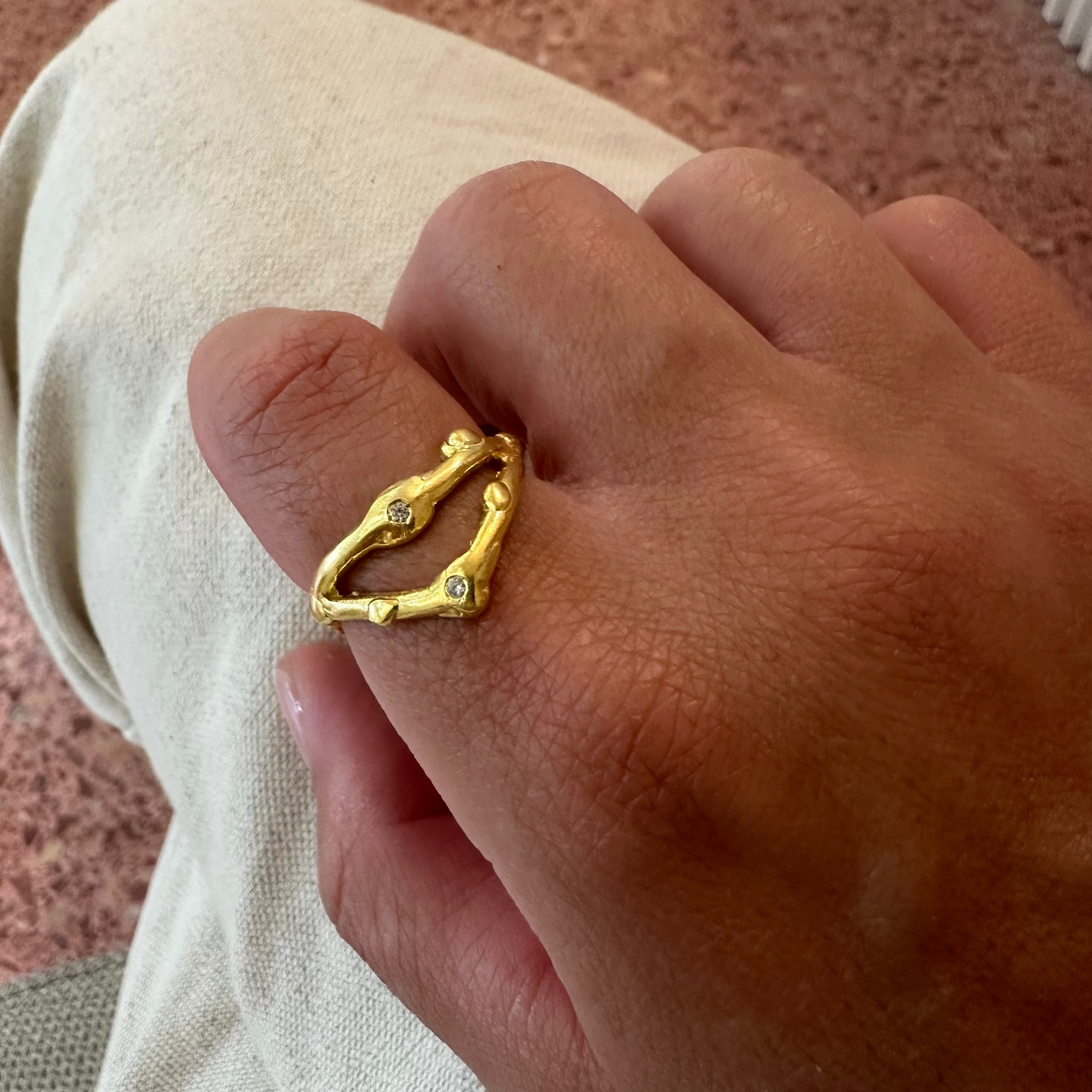 Gold ring with small stones on a finger against a neutral background