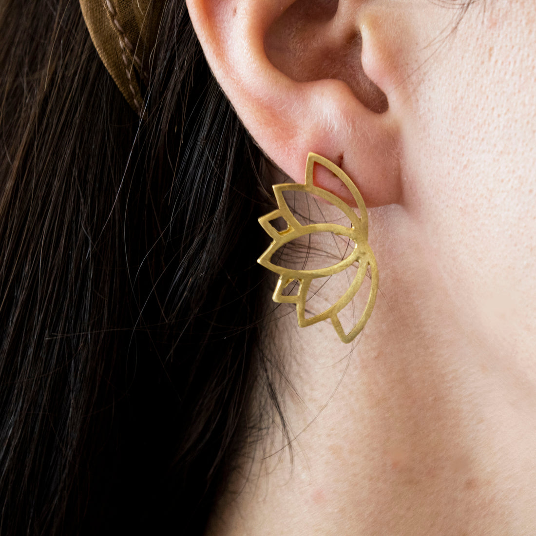 Gold lotus flower earrings on a white background