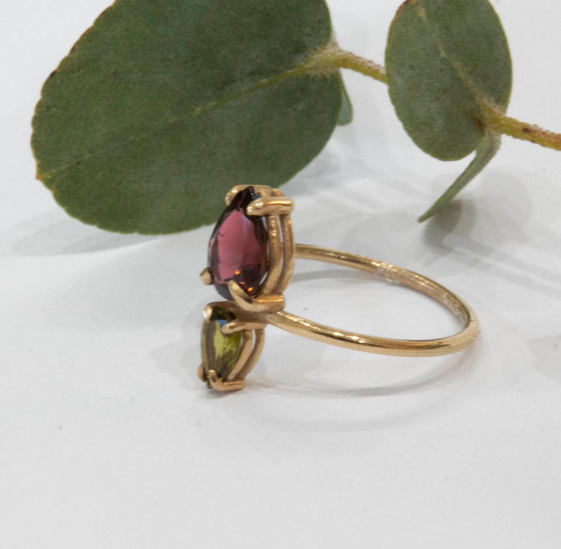 Gold ring with a green and red gemstone on a white background