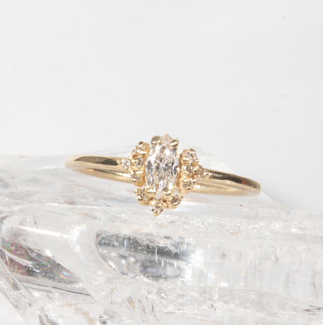 Gold ring with a marquise-shaped diamond on a white background