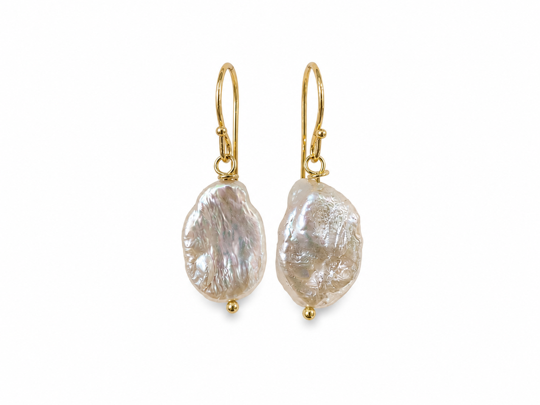 Gold earrings with large, irregularly shaped pearl-like stones on a white background