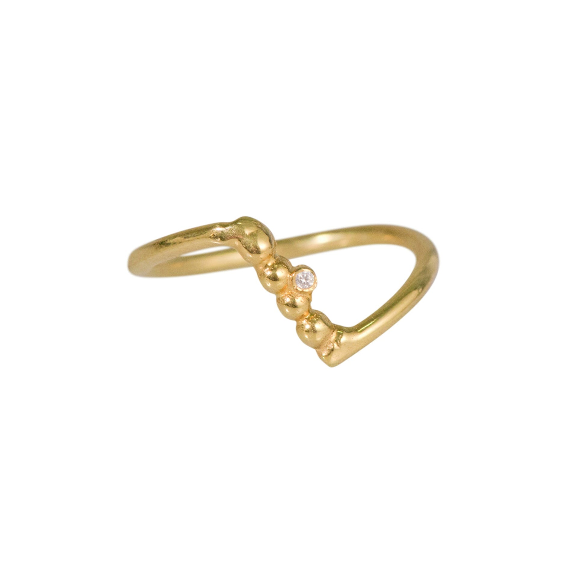 A gold-colored ring with a simple band and a small heart-shaped charm with a zircon stone.