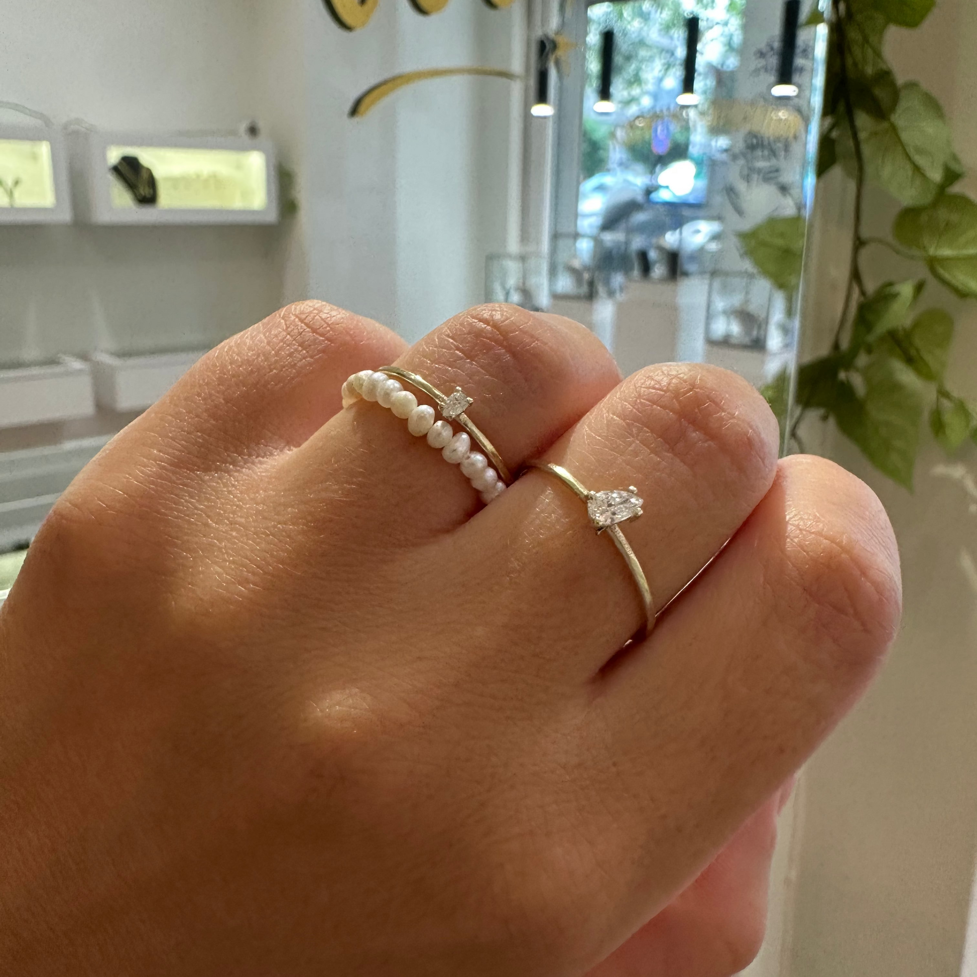 Hand wearing two rings with a blurred indoor background