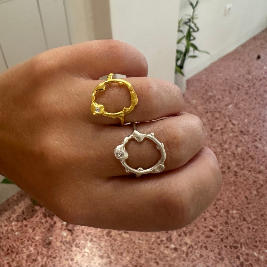 A gold-plated ring with a small round clear gemstone set on one of the lower tips, photographed on a clean white background.