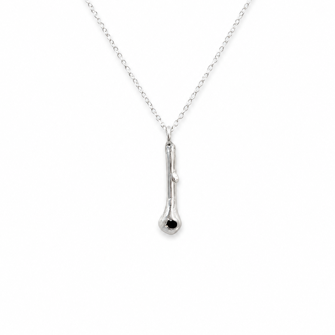 A delicate silver chain necklace featuring a small, polished silver pendant with a single tiny black gemstone accent at the bottom, shown against a plain white background.