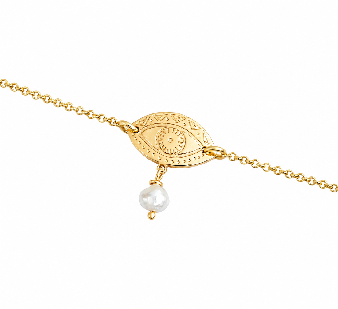 Gold-plated bracelet with an eye-shaped pendant and a pearl on a white background