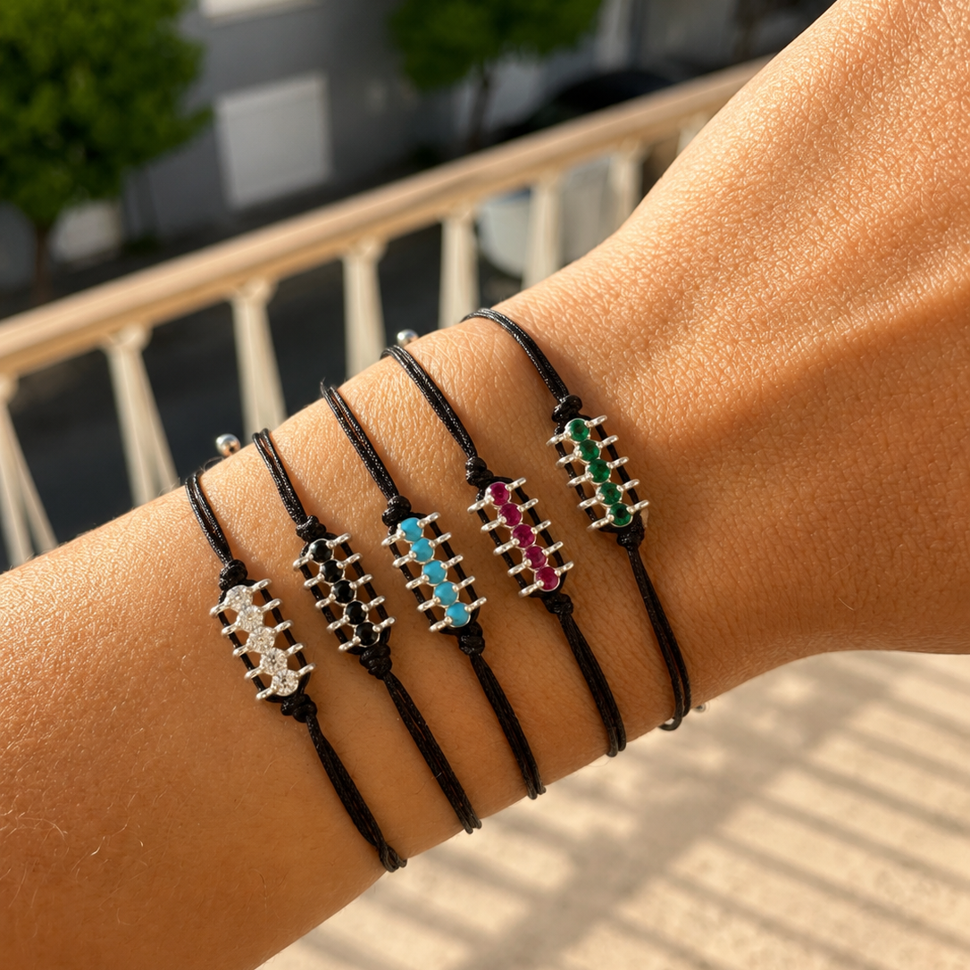 Close-up of a wrist wearing multiple black cord bracelets with colorful beads.